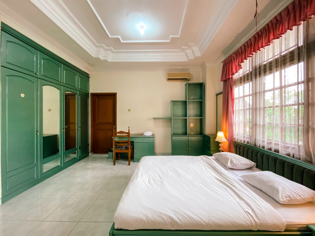 A comfortable bedroom equipped with study table and wardrobe at quiet academic guesthouse near UGM